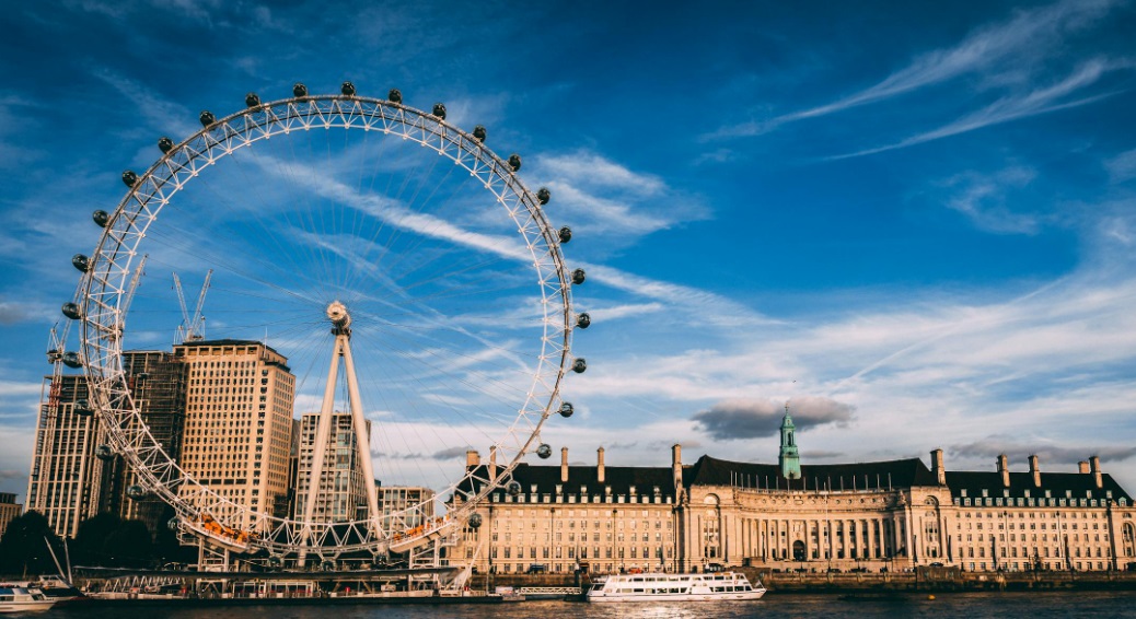 London Eye Ferris wheel beside the River Thames under a bright blue sky